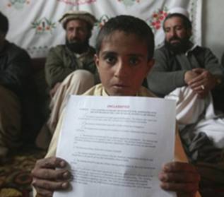 The son of Hafizullah Shahbaz Khiel, who has been held since last September at Bagram Air Base, Afghanistan, as a US prisoner, holds up papers declaring his innocence. (Photo: Rafiq Maqbool / AP)