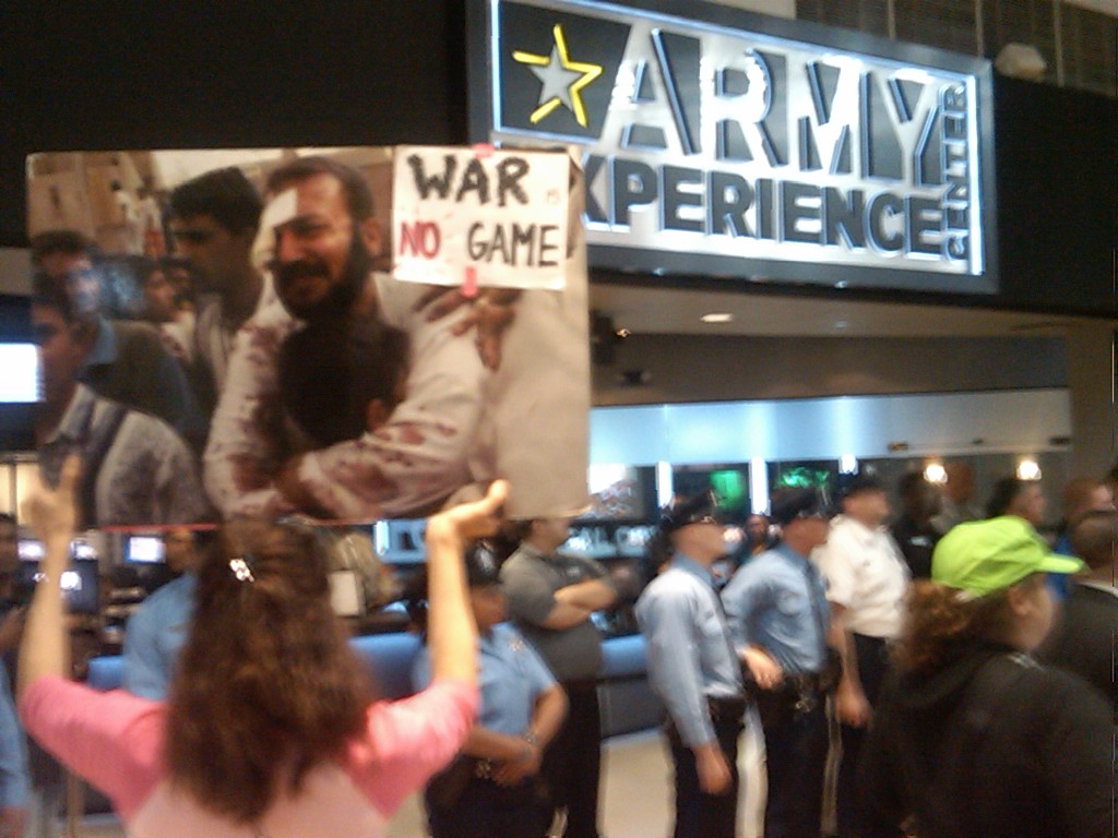 Photographer:  Copyright 2009, Paul Kawika Martin. CodePink’s Desiree Fairooz holds sign.  Nearly 300 veterans, military families and peace activist shut down what they called the unethical teenage recruitment at the “Army Experience Center.”  Seven were arrested for refusing to leave.