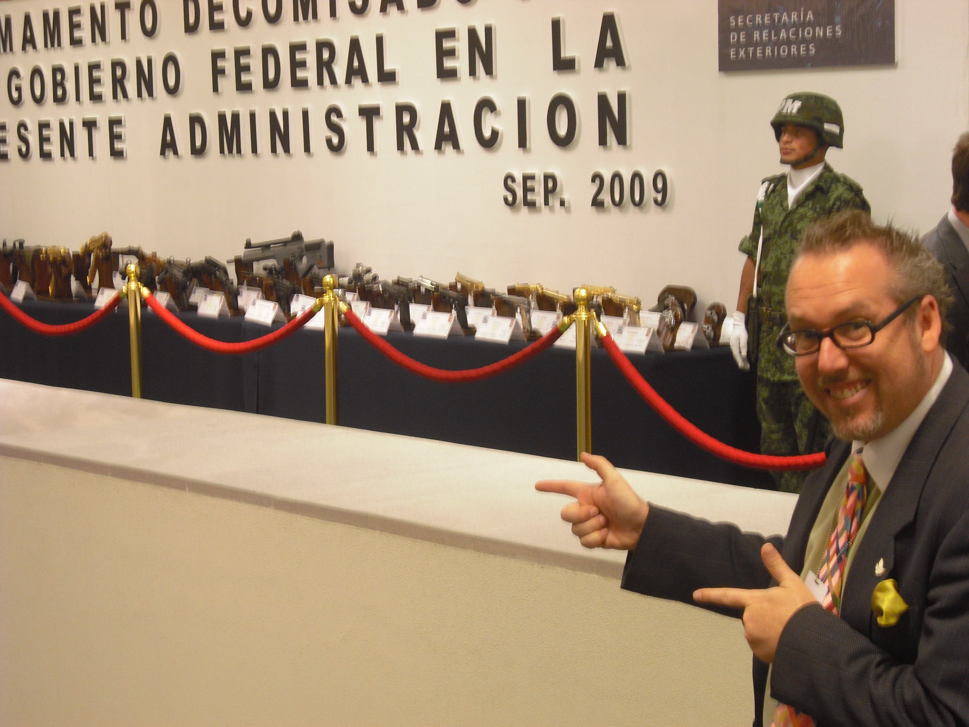 Peace Action Organizing and Policy Director Paul Kawika Martin points to weapons confiscated by the Mexican goverment (this display was in the Foreign Ministry right next to our conference!) 